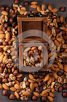 Wooden box full of nuts. Mix of hazelnuts, walnuts and almonds on the table, vertical frame
