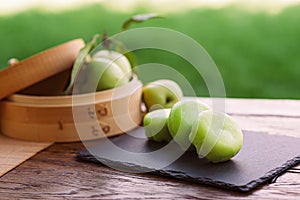 A wooden box of green apples, a natural food, sits on a table made of wood. Mochi asian dessert