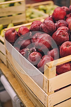 Wooden box of red apples in shop, supermarket, fruit department. Fresh ripe seasonal fruits, autumn vitamin harvest. Shop local