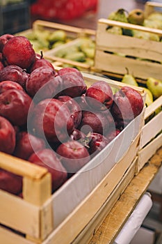 Wooden box of red apples in shop, supermarket, fruit department. Fresh ripe seasonal fruits, autumn vitamin harvest. Shop local
