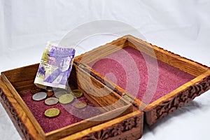 Wooden box with red carpet, coins and Swedish krona banknote