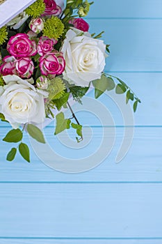 Wooden box with white and pink roses and chrysanthemums on turquoise wooden board. Decoration of home. Flowers boxes. Wedding