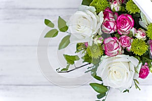 Wooden box with white and pink roses and chrysanthemums on  white wooden board. Decoration of home. Flowers boxes. Wedding