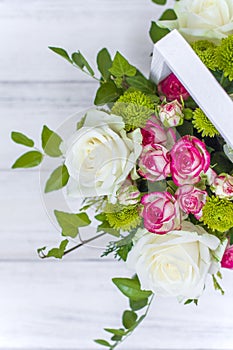 Wooden box with white and pink roses and chrysanthemums on  white wooden board. Decoration of home. Flowers boxes. Wedding