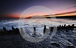 Wooden breakwaters in The Mudflats at dawn