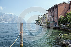 Wooden bricole for boats in the water, lake Lago Di Garda, morning light, mountains on the background photo