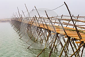 Wooden bridge across the misty river.