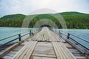 Wooden bridge across mountain stream. Altai Republic, Russia