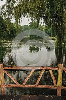 Wooden bridge amid gardens with trees on a rainy day at De Haar Castle, near Utrecht.