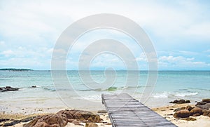 Wooden bridge on the beach and rocks,,cloudy and blue sky , summer background