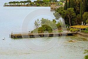 Wooden bridge within a beautiful scenery at Lake Garda in Sirmione, Italy.