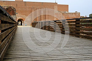 Wooden bridge and brick castle walls. Novara Castle renovated with new walls and buttresses