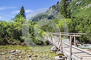 Wooden bridge crossing a stream at the hiking path to Popradske Pleso