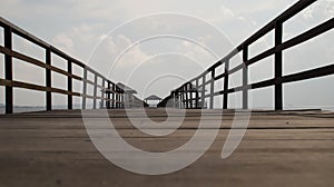 Wooden bridge dock or pier or boardwalk jetty for ship to dock at the shore. Low angle view