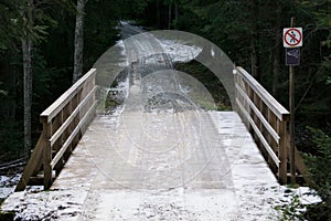 Wooden bridge in the forest. Snow covered road