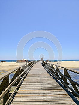 Wooden bridge and Isla Cristina beach in the background, Costa de la Luz, Huelva, Spain in front Punta del Moral village,