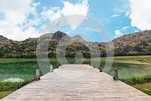 Wooden bridge or jetty with mountain and blue sky on lake