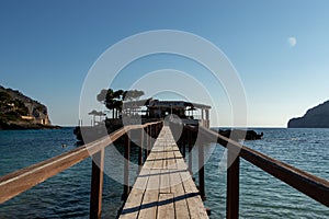 Wooden bridge leading across Sea to an island with an restaurant in camp de mar, mallorca, spain