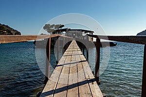 Wooden bridge leading across Sea to an island with an restaurant in camp de mar, mallorca, spain