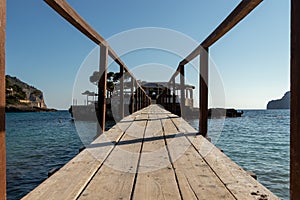 Wooden bridge leading across Sea to an island with an restaurant in camp de mar, mallorca, spain