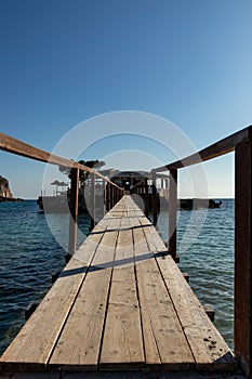 Wooden bridge leading across Sea to an island with an restaurant in camp de mar, mallorca, spain