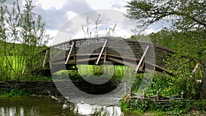 Wooden bridge over creek with braided wicker railing