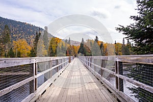 Wooden Bridge Over Jacques-Cartier River Surrounded by Colorful Fall Foliage, Quebec, Canada