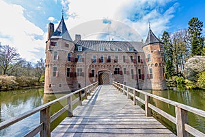 Wooden bridge over the moat, leading to the gate to Het Oude Loo castle surrounded by trees