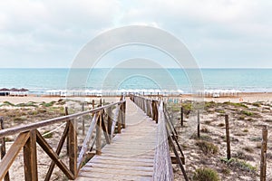 Wooden bridge over the protected dunes to access the beach umbrellas in Guardamar. Alicante, Spain