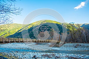 Wooden bridge over river natural green mountain and blue sky background in fall season at kamikochi Japan