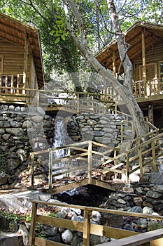 Wooden bridge over a small stream in the forest. Waterfall in the garden with rocks and leaves in autumn season.