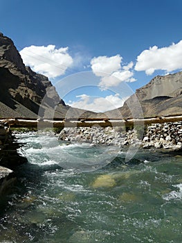 Wooden bridge over the stormy mountain river