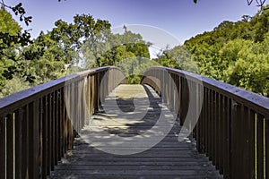 Wooden bridge in a park with green trees in the background. Clearlake, California