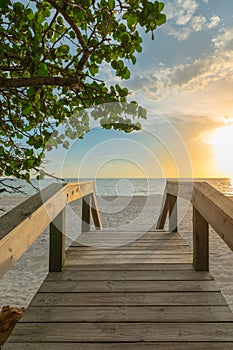 Wooden bridge on the sandy beach at sunset. Naples Beach, Florida