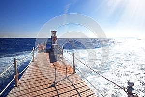 Wooden bridge to the blue ocean ,sun is shining brightly in blue sky