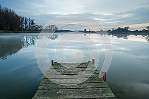 Wooden bridge towards a misty and calm lake