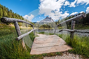 Wooden bridge wide angle photo on Italian  Lago d`Antorno or Antorno Lake with stunning Tre Cime di Lavaredo 2999m peaks on the