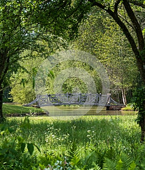 Bridge over water surrounded by trees at West Green House landscaped gardens in Hartley Wintney, Hampshire, UK