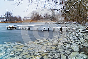 Wooden bridges covered with snow on a beautiful frozen river surrounded by trees of rural background