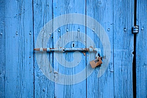 Wooden bright blue, empty, old door for background. Rusty latch, padlock. Close up, banner, details