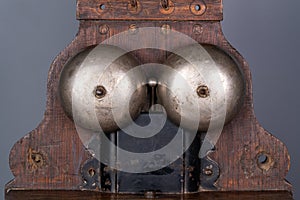 Wooden brown antique apparatus with two metal hemispheres for signaling call. Old school bell. Retro phone mechanism for