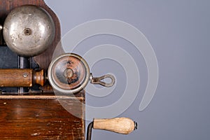 Wooden brown antique telephone apparatus with handset and handle. Vintage shabby phone with two metal hemispheres for