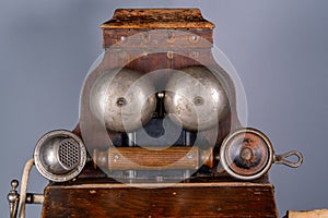 Wooden brown antique telephone apparatus with handset. Vintage shabby phone with two metal hemispheres for signaling