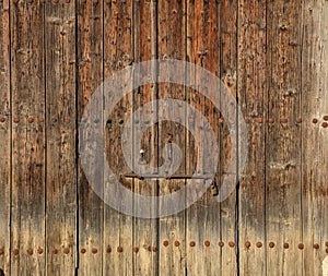 Wooden brown timeworn door. Space for text backdrop, rusty latch and padlock. Closeup view, details.
