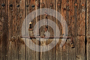 Wooden brown empty timeworn door. Space for text backdrop, rusty latch and padlock. Closeup, details