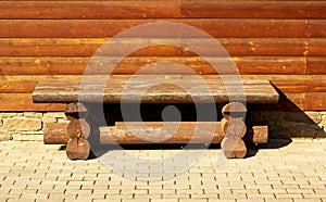 Wooden brown log bench  against the wooden wall background. Concept