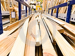 Wooden brown sawn natural building boards stick logs with knots on a rack on a sawmill in the store. The background