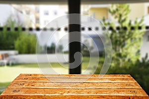 Wooden brown table top against the blurred corridor, passage and courtyard of the house .For product display montage or