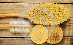 Wooden brush for dry body massage, porous sponge. Anti-cellulite brush for body and leg massage on a wooden background