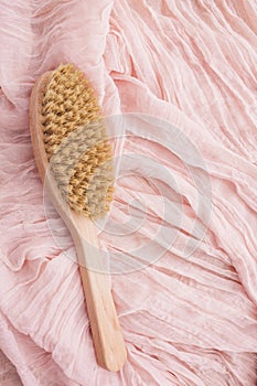 Wooden brush on pink background for dry massage. The aesthetics of wabi sabi. Natural material